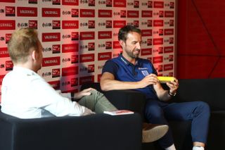 Gareth Southgate holds a yellow packet of custard cream biscuits given to him in a Vauxhall car dealership in Milton Keynes by young fans. Match of the Day writer / presenter Matthew Ketchell looks on